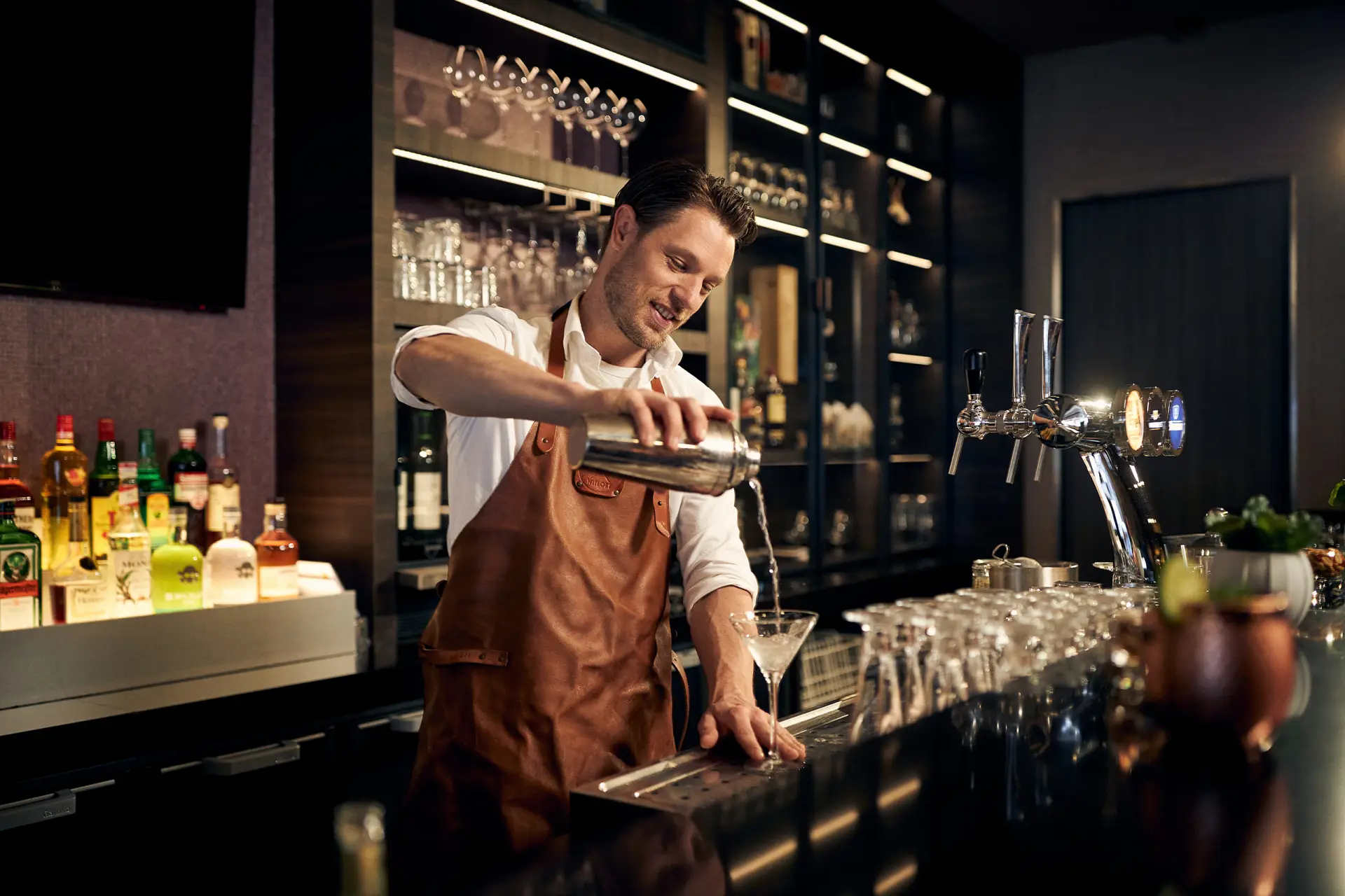 Barman die een cocktail inschenkt achter de bar