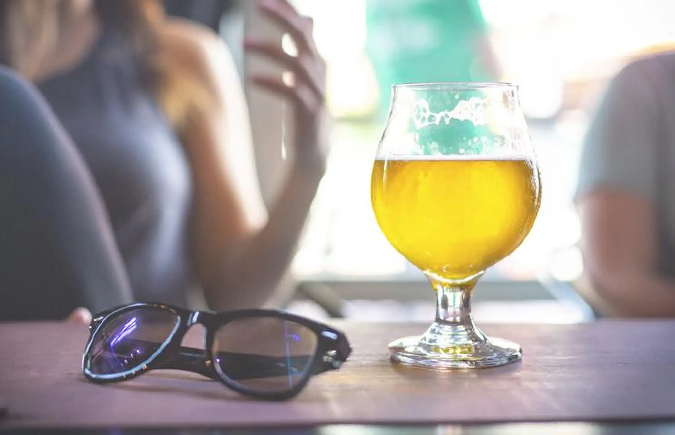 Glas bier en zonnebril op tafel in café