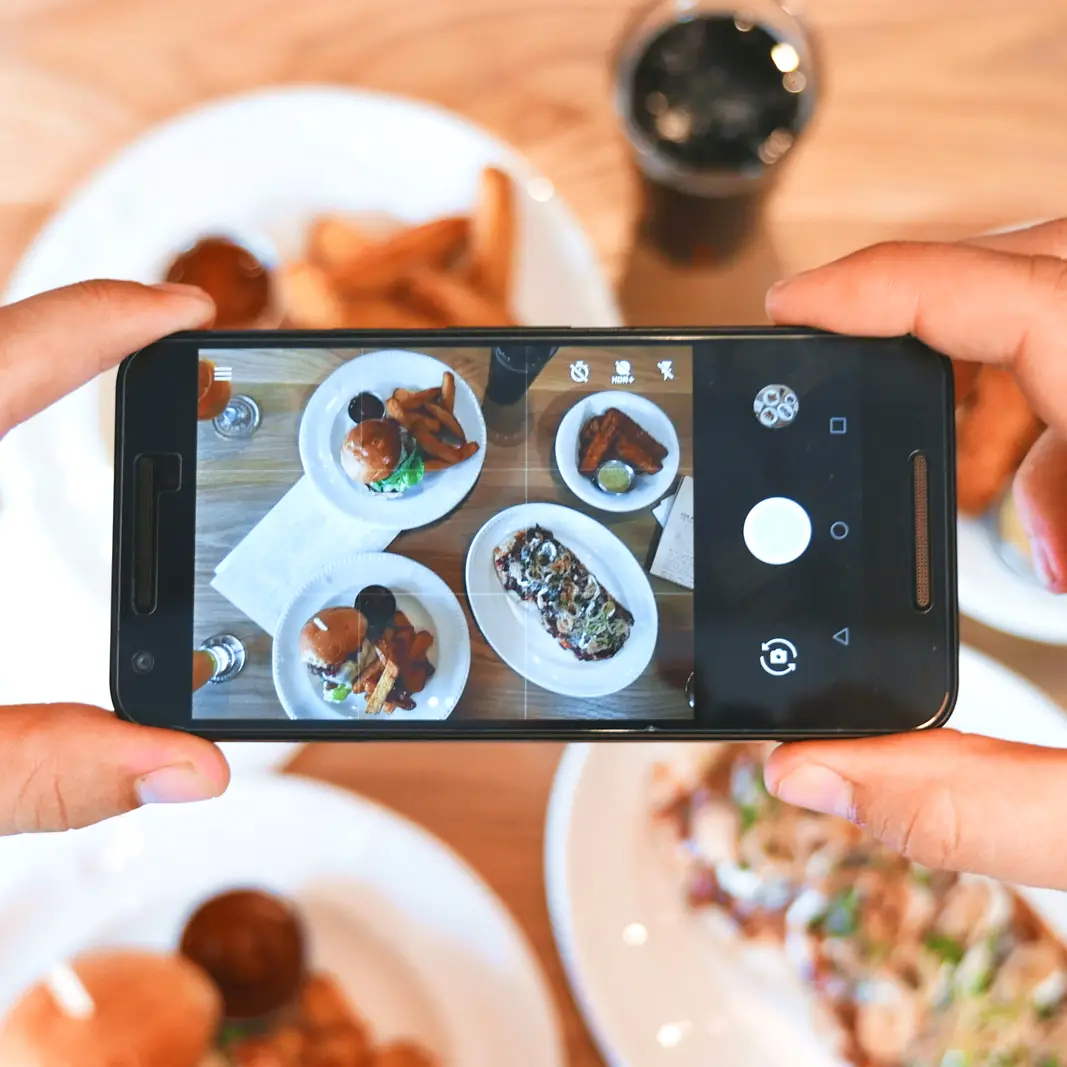 Horecaondernemer maakt met telefoon foto van gerechten voor op social media
