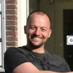 Lachende man in de zon voor zijn restaurant