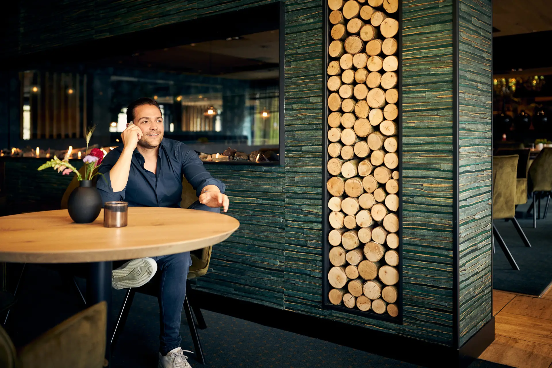 Man die aan een tafel zit in een restaurant en aan het bellen is