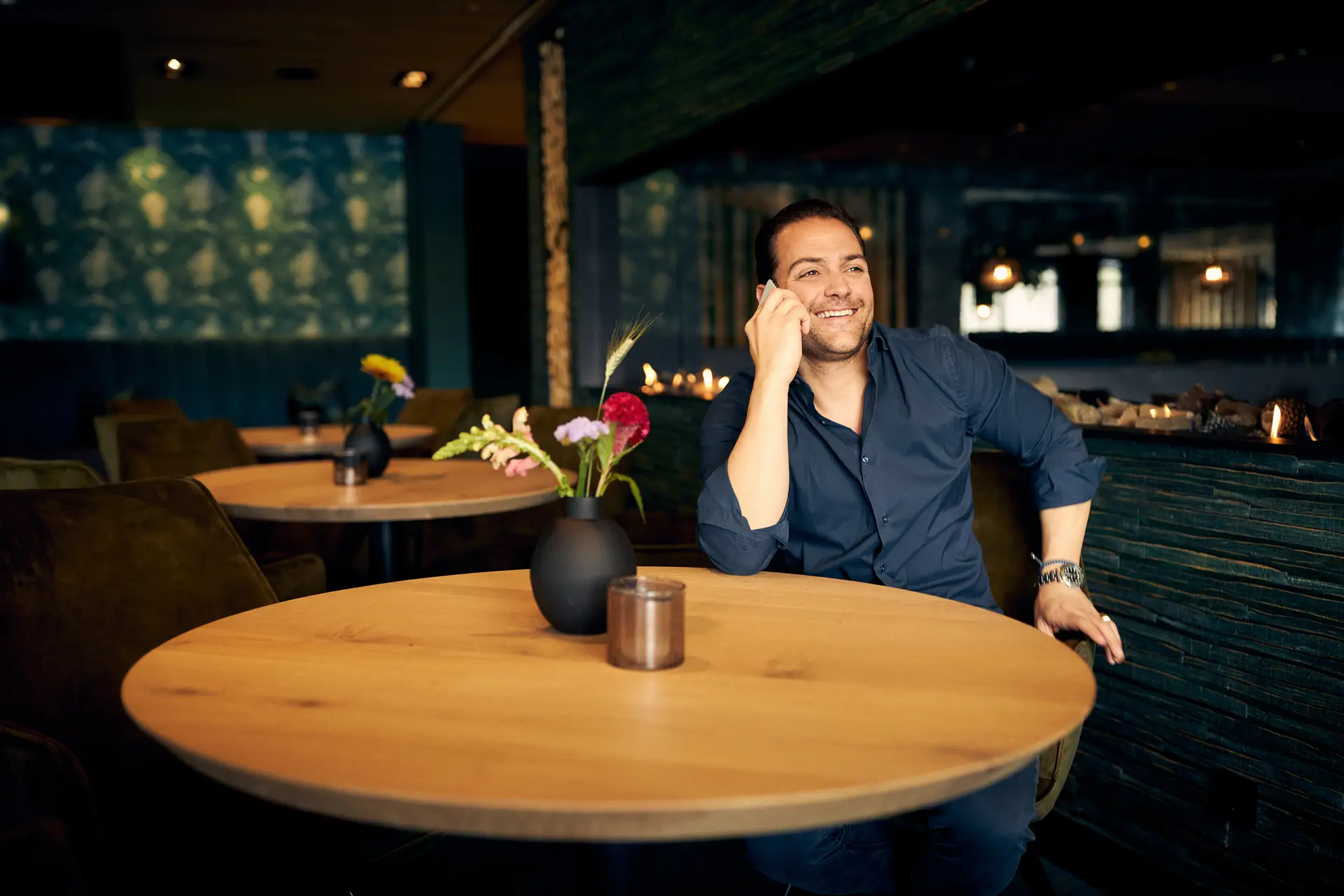 Man die aan een tafel zit in een restaurant en aan het bellen is