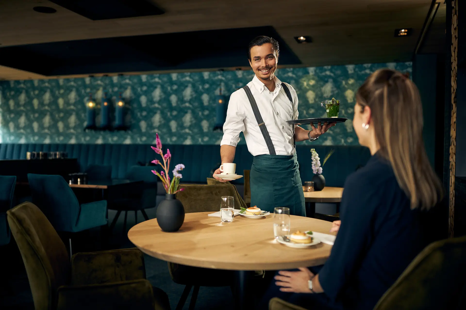 Mannelijke ober die een bord eten neerzet op tafel in een restaurant