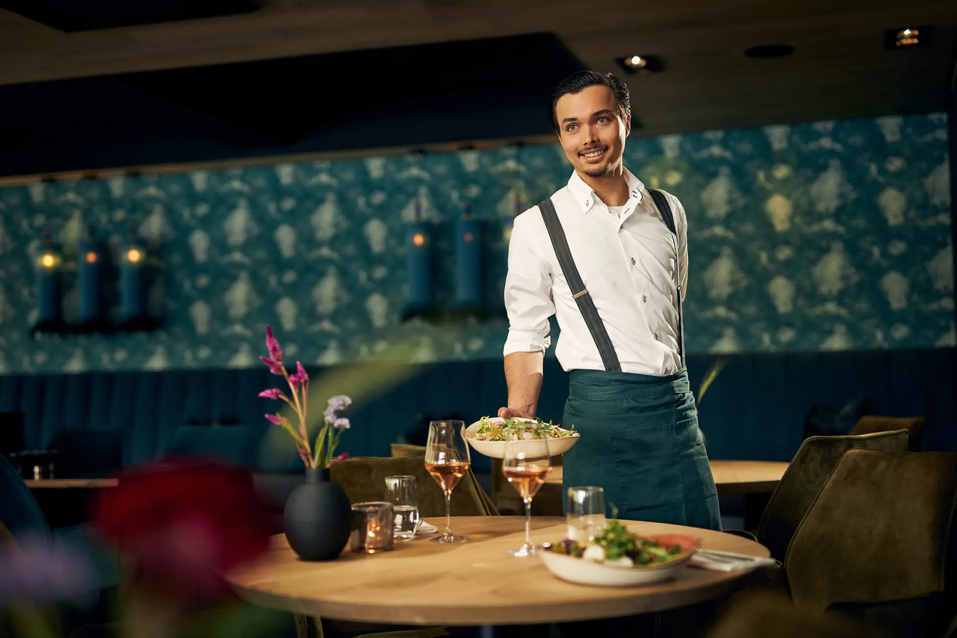 Mannelijke ober die een bord eten neerzet op tafel in een restaurant