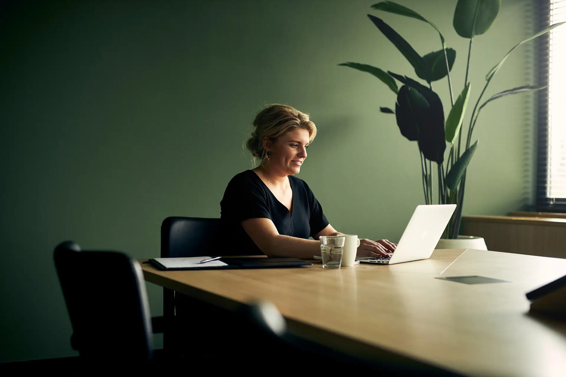 Vrouw die op een laptop werkt in een vergaderruimte
