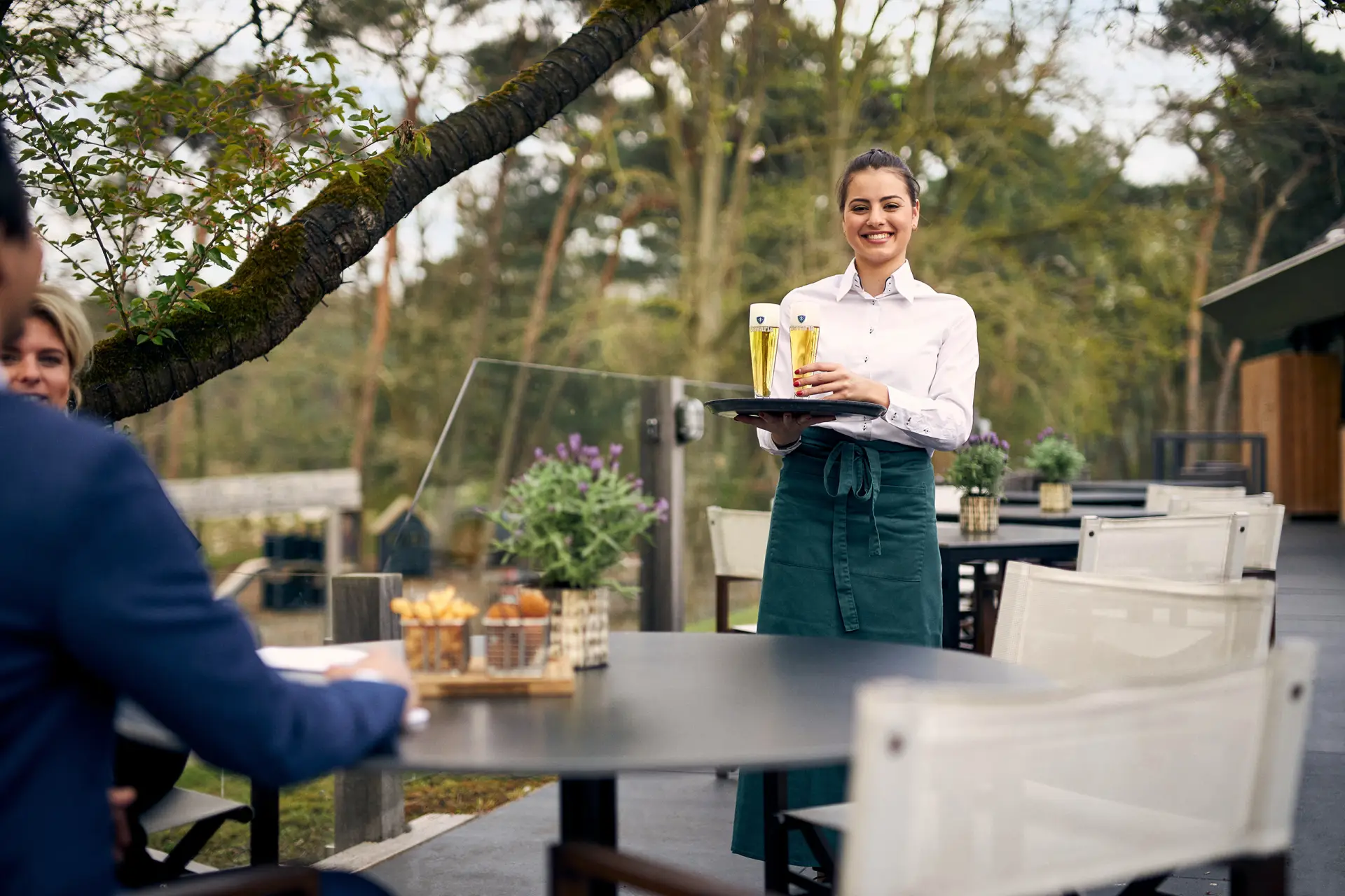 Vrouwelijke ober die buiten op het terras een drankje komt brengen